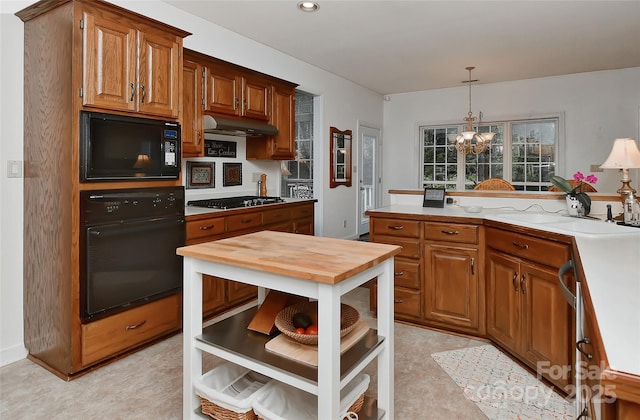 kitchen with hanging light fixtures, sink, an inviting chandelier, and black appliances