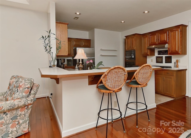 kitchen with appliances with stainless steel finishes, light wood-type flooring, a kitchen breakfast bar, and kitchen peninsula