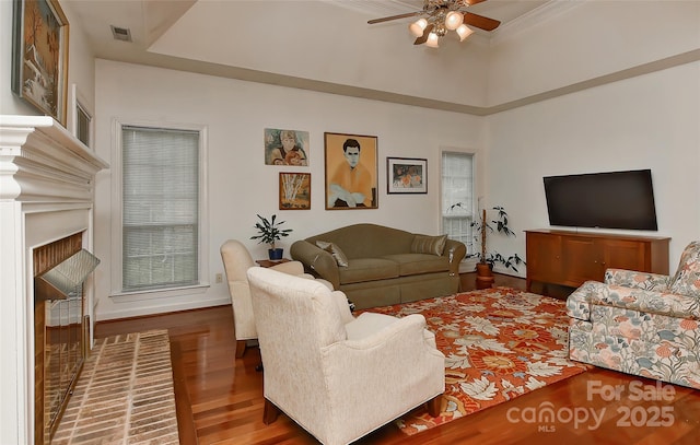 living room featuring ceiling fan, ornamental molding, a tray ceiling, and hardwood / wood-style floors