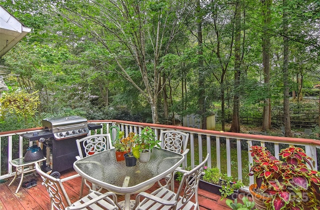 wooden terrace featuring area for grilling and a storage unit