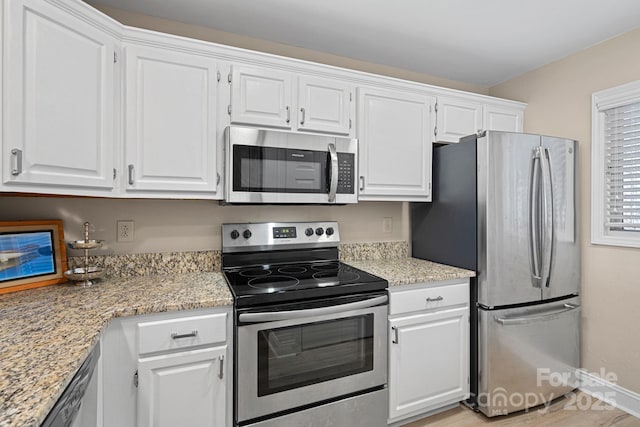 kitchen featuring appliances with stainless steel finishes, white cabinets, and light stone counters