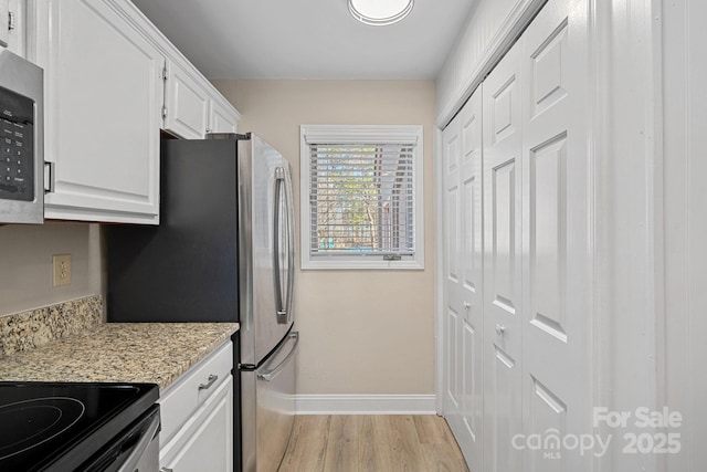 kitchen with light stone countertops, stainless steel appliances, light hardwood / wood-style floors, and white cabinets