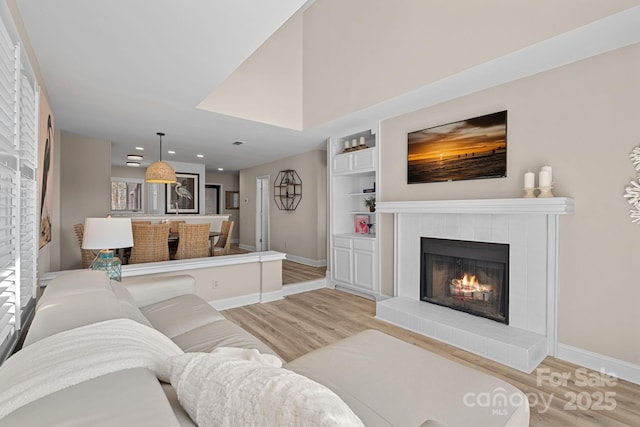 living room with a tile fireplace and light wood-type flooring