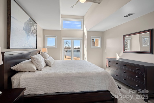 bedroom with a water view, access to exterior, and light hardwood / wood-style floors