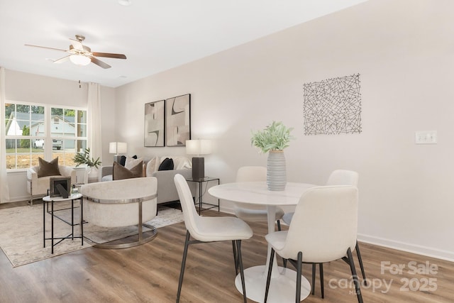 dining area featuring wood finished floors, a ceiling fan, and baseboards