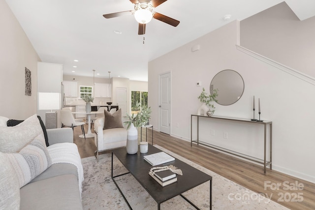 living area with recessed lighting, ceiling fan, light wood-style flooring, and baseboards