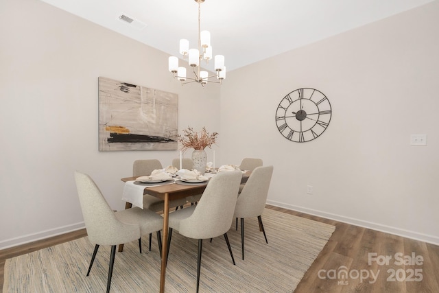 dining room with dark wood-type flooring, a chandelier, visible vents, and baseboards