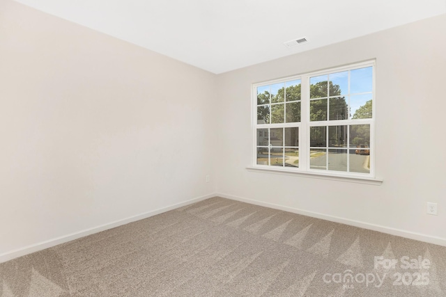 carpeted empty room with visible vents and baseboards