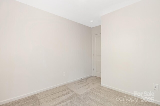 empty room featuring baseboards and light colored carpet