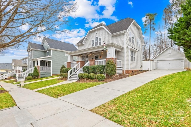 view of front of home with a porch, a garage, a front yard, and an outdoor structure