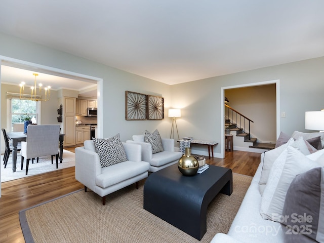 living area with an inviting chandelier, baseboards, stairway, and wood finished floors