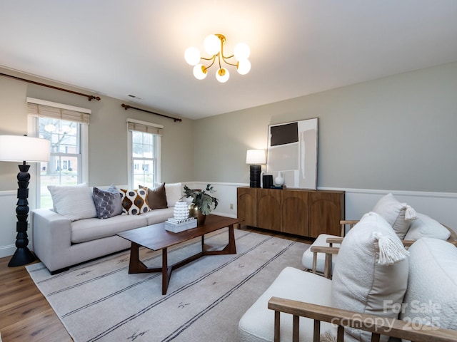 living room with light wood finished floors, visible vents, and a notable chandelier