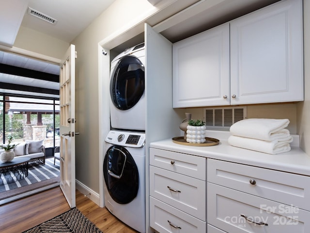 laundry area featuring stacked washer and dryer, laundry area, visible vents, and light wood-style floors