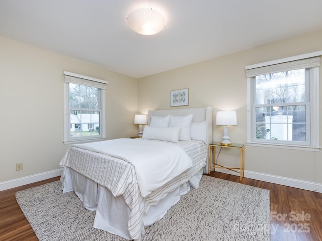 bedroom featuring multiple windows, baseboards, and wood finished floors