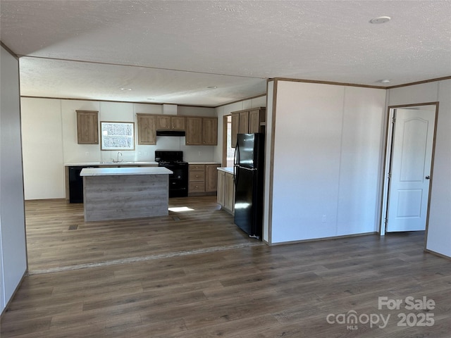 kitchen with dark wood-style floors, black appliances, a kitchen island, and light countertops