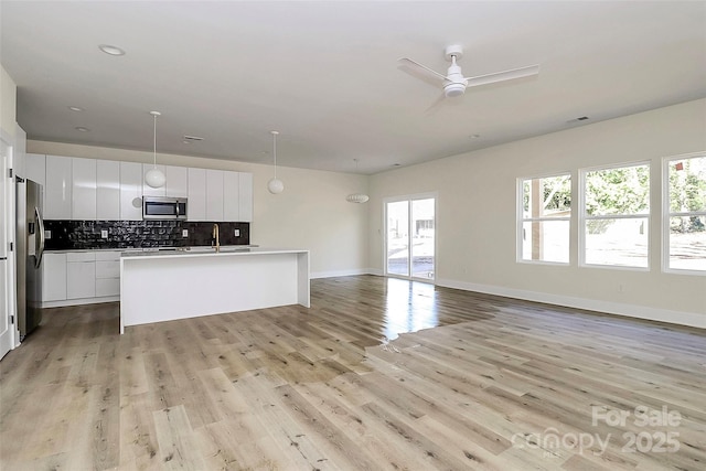 kitchen featuring white cabinetry, sink, backsplash, hanging light fixtures, and stainless steel appliances