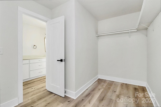 walk in closet with light hardwood / wood-style flooring