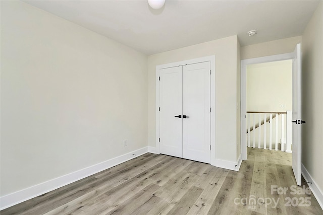 unfurnished bedroom with light wood-type flooring and a closet