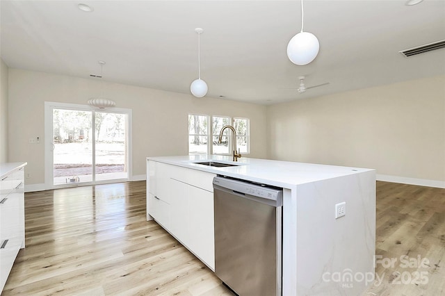 kitchen with an island with sink, white cabinetry, sink, hanging light fixtures, and stainless steel dishwasher