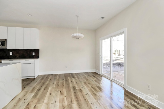 kitchen featuring white cabinetry, pendant lighting, light hardwood / wood-style floors, and decorative backsplash