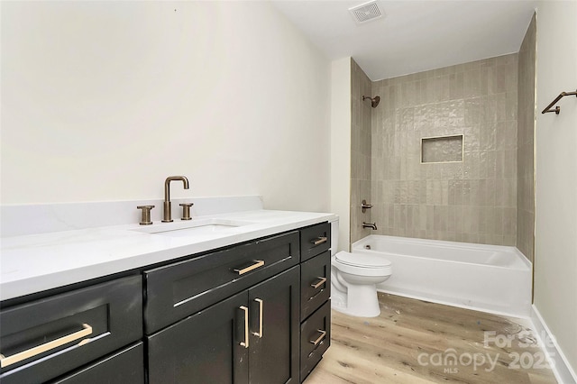 full bathroom featuring vanity, tiled shower / bath combo, wood-type flooring, and toilet