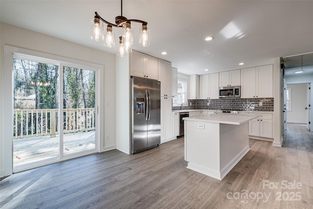 kitchen featuring decorative light fixtures, light hardwood / wood-style flooring, stainless steel appliances, and white cabinets