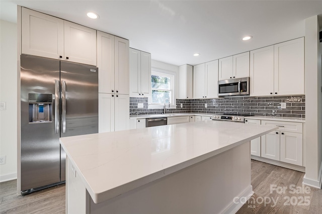 kitchen with white cabinetry, a kitchen island, tasteful backsplash, and appliances with stainless steel finishes