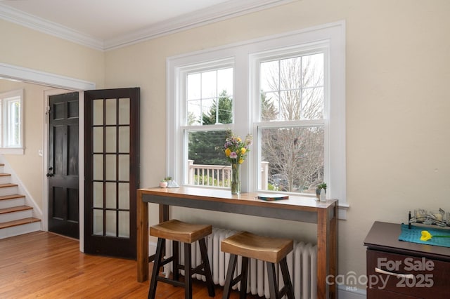 interior space with stairway, crown molding, light wood finished floors, and radiator heating unit