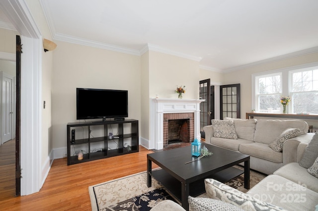 living room with light wood-type flooring, a brick fireplace, baseboards, and ornamental molding