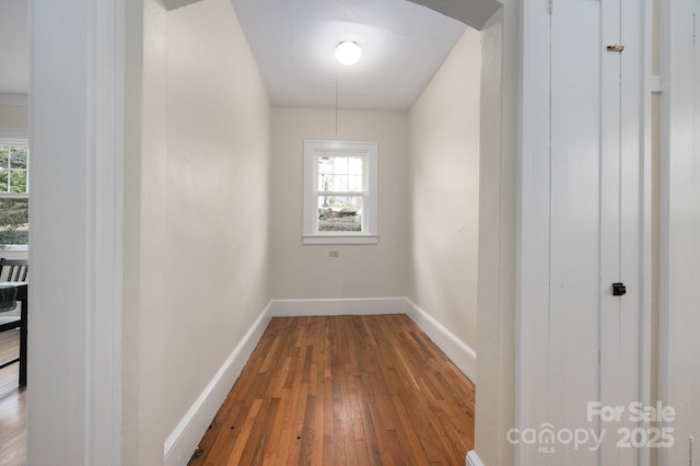 corridor with baseboards and wood finished floors