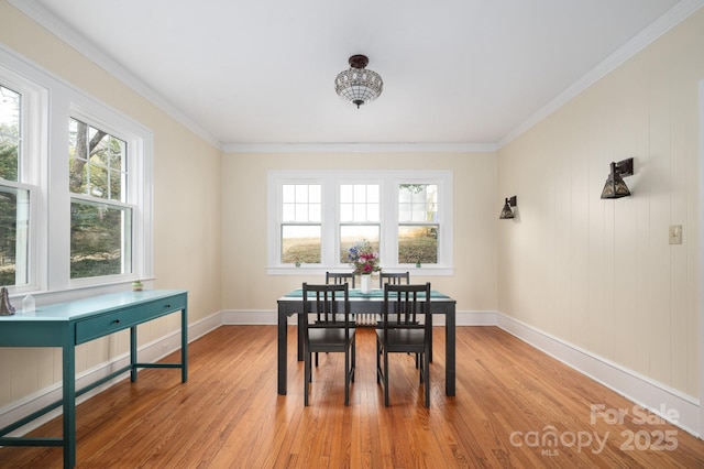 dining room featuring light wood-type flooring, baseboards, and crown molding