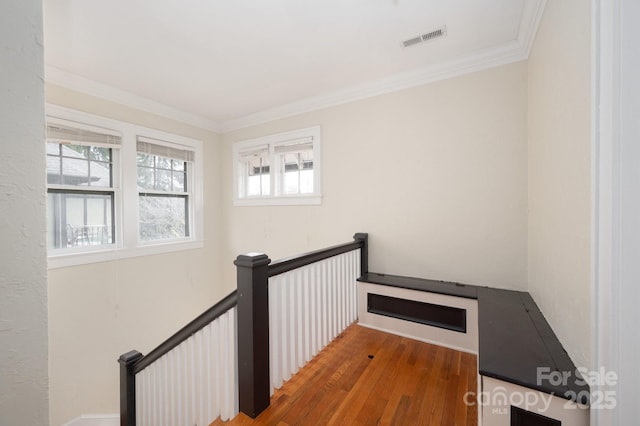 hall with ornamental molding, visible vents, wood finished floors, and an upstairs landing