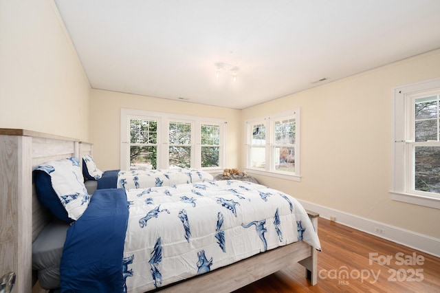 bedroom with visible vents, baseboards, and wood finished floors