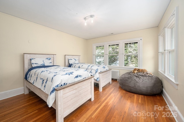 bedroom featuring baseboards, radiator, and wood finished floors