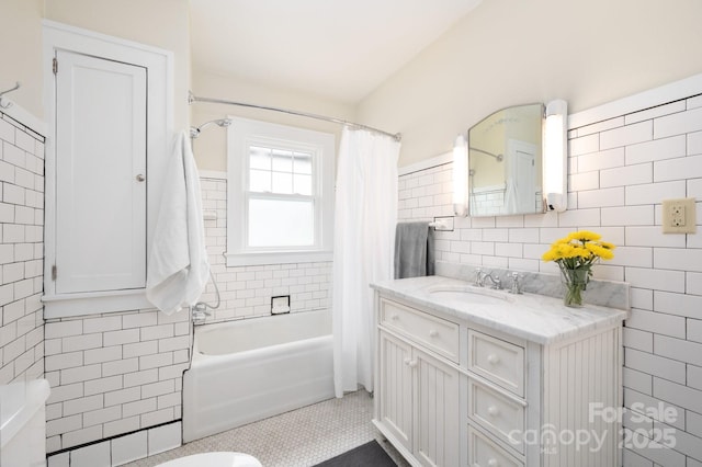 full bathroom with vanity, toilet, tile walls, and shower / bath combo with shower curtain