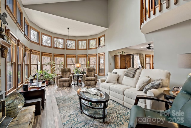 living area with ceiling fan, a high ceiling, and wood finished floors