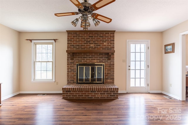 unfurnished living room featuring ceiling fan, dark hardwood / wood-style floors, a fireplace, and a textured ceiling