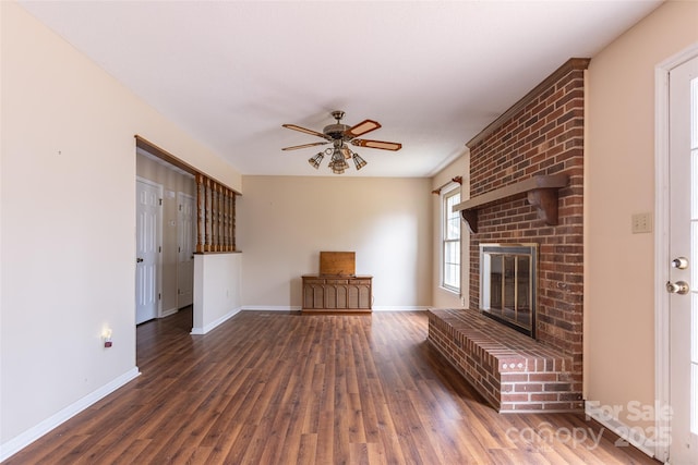 unfurnished living room with ceiling fan, dark wood-type flooring, and a fireplace