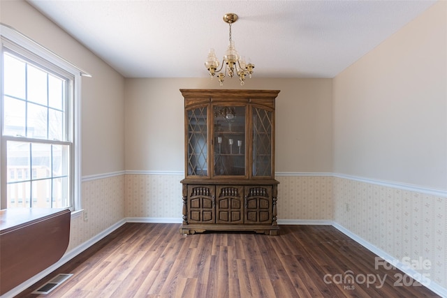 spare room with dark wood-type flooring and a chandelier