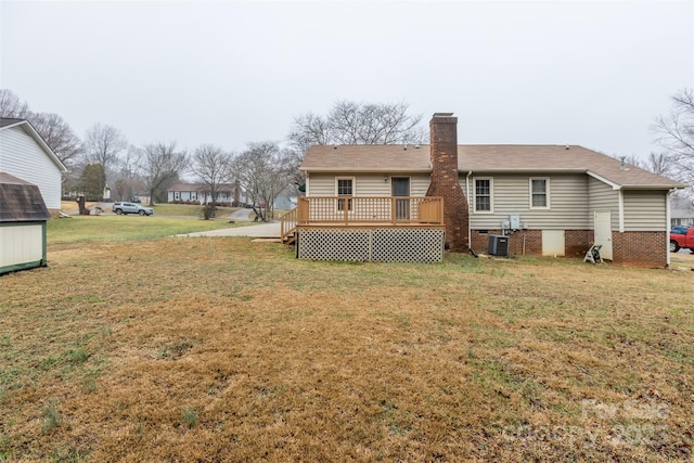 back of property with a wooden deck, central AC, and a lawn