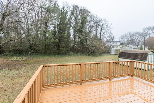 wooden deck with a storage unit and a lawn