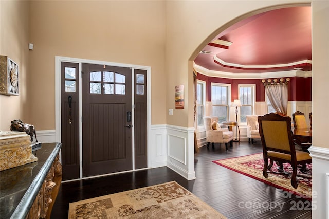 foyer entrance with crown molding and dark wood-type flooring