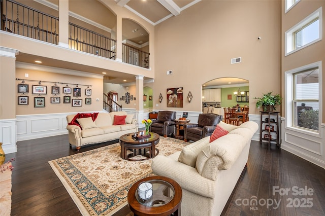 living room featuring crown molding, dark hardwood / wood-style floors, decorative columns, and a notable chandelier