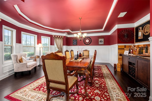 dining room with dark wood-type flooring, sink, an inviting chandelier, and a tray ceiling