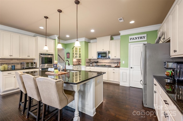 kitchen with an island with sink, sink, a kitchen bar, hanging light fixtures, and stainless steel appliances