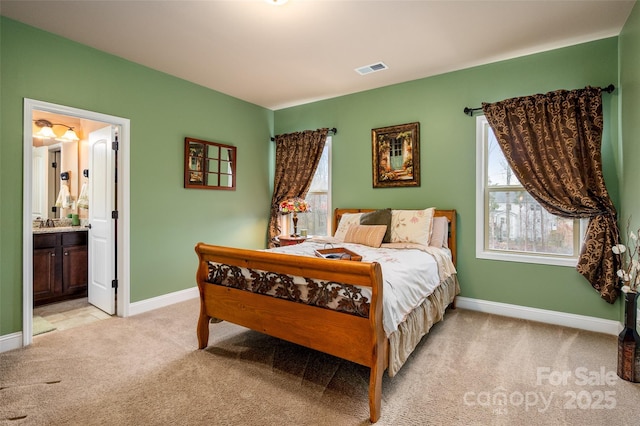 bedroom featuring connected bathroom and light carpet