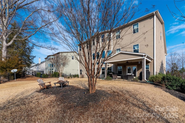 rear view of house with ceiling fan and an outdoor fire pit