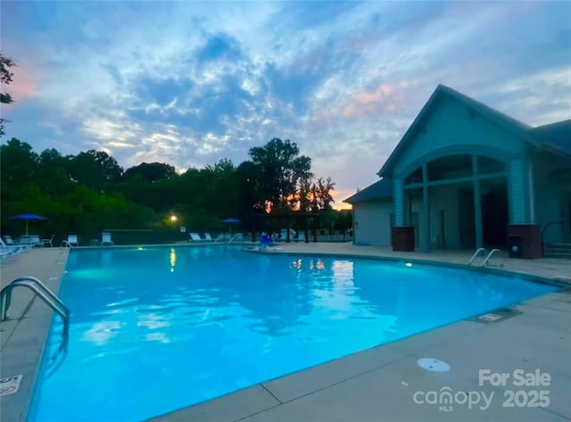 pool at dusk with a patio area