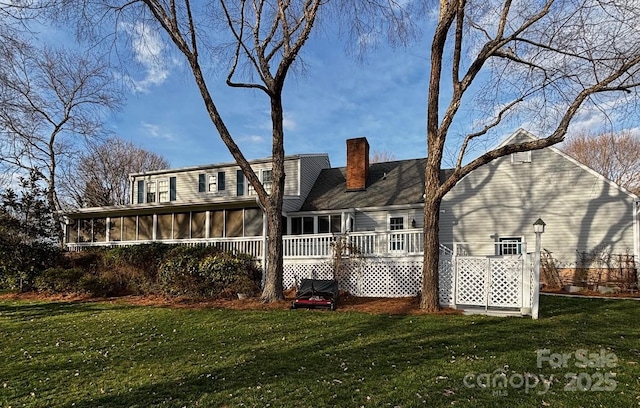 rear view of house featuring a sunroom, a yard, and a chimney