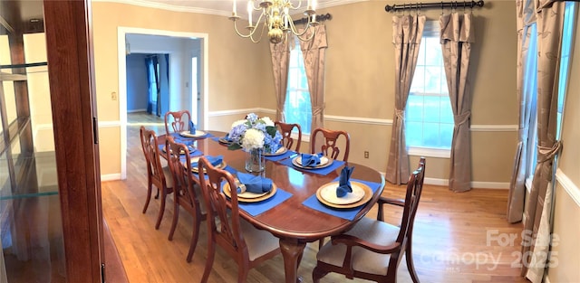 dining area featuring a chandelier, crown molding, baseboards, and wood finished floors